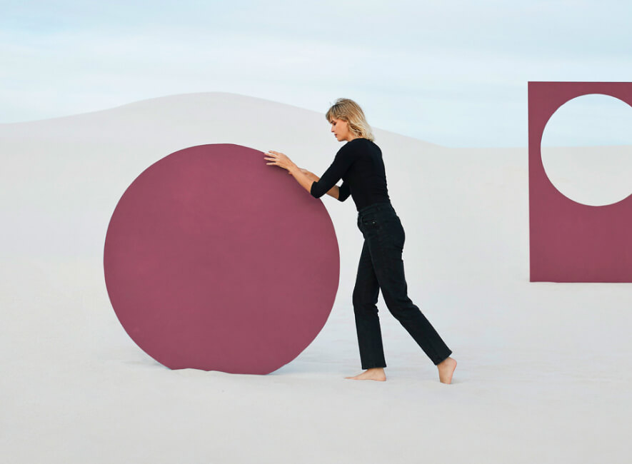 Woman pushing a huge circle in the desert