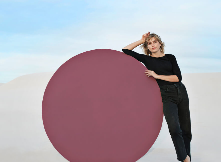 Woman leaning against a huge circle in the desert