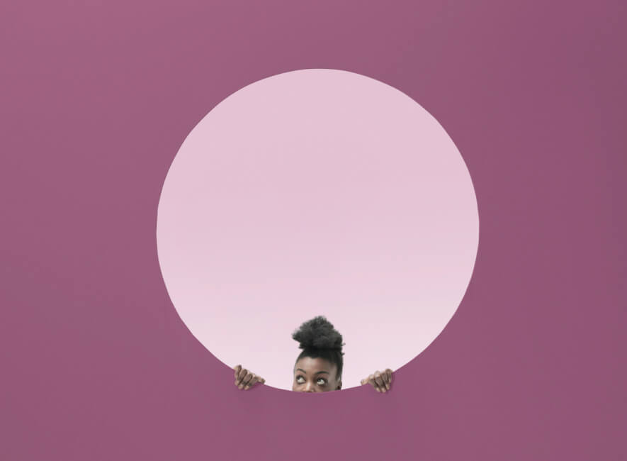 Woman looking out of a circle inside a wall